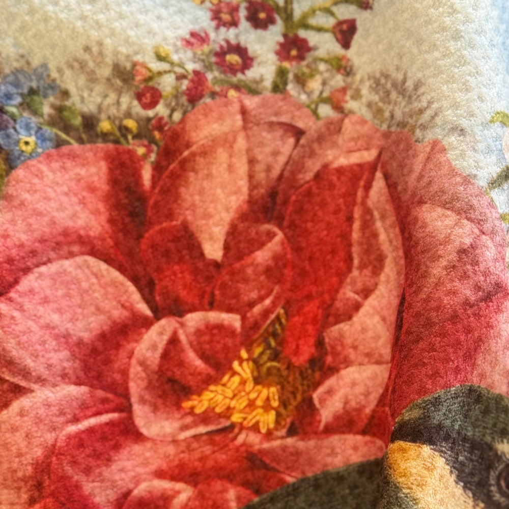 Close-up of a textured fabric with a red flower design and a small bird.