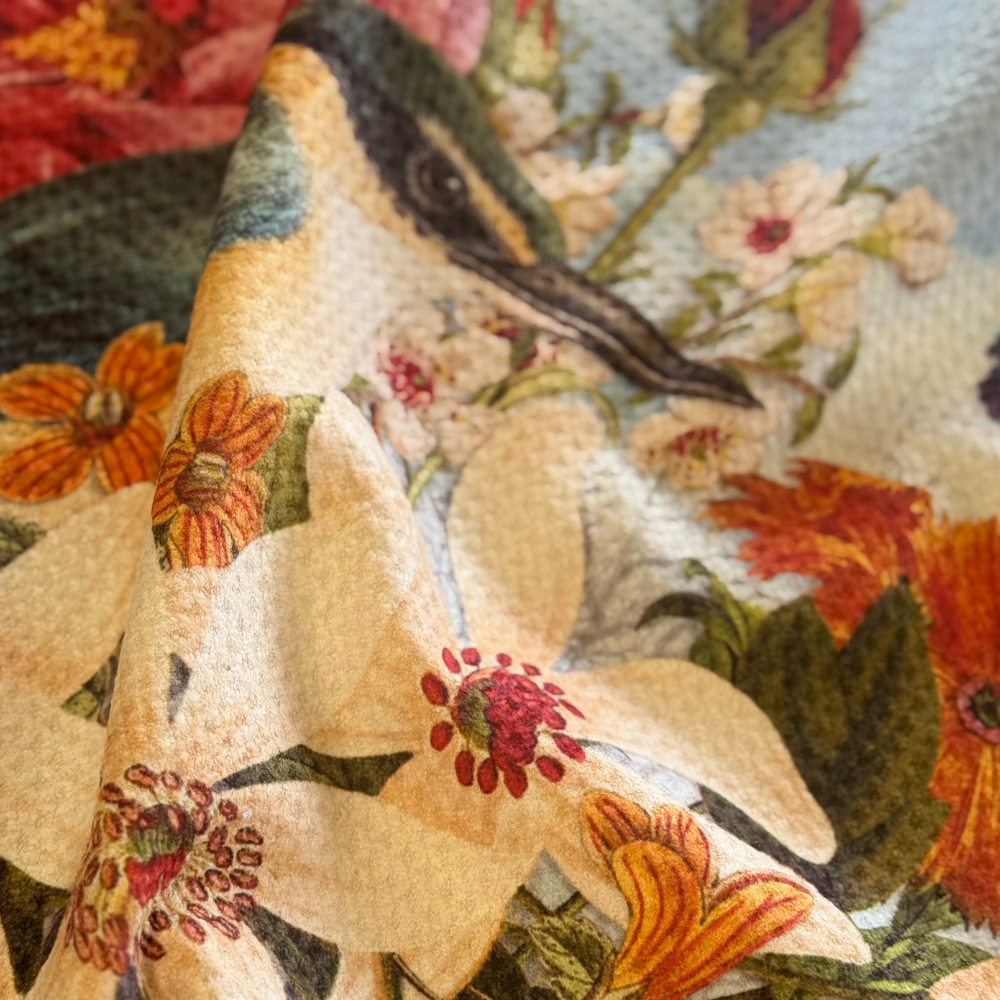 Close-up of a decorative fabric with floral patterns and a bird design.